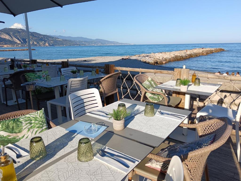 - un restaurant avec des tables et des chaises sur la plage dans l'établissement Appartement équipé, Roquebrune Menton plage mer ., à Roquebrune-Cap-Martin