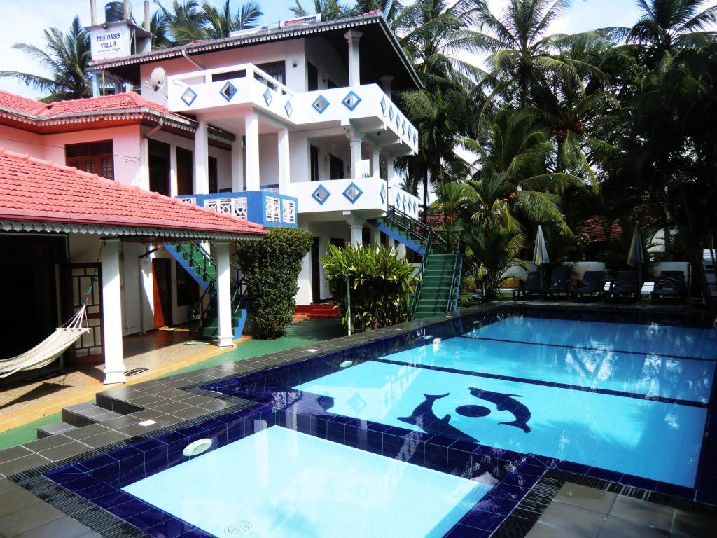 a swimming pool in front of a house at The Oasis Villa in Hikkaduwa