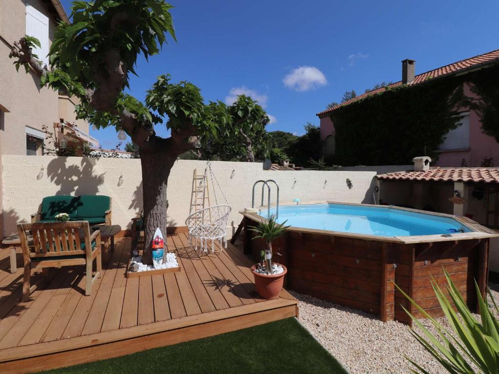 a pool on a wooden deck with a tree at Beau 3 pièces climatisé, piscine privée, parking au Grau-du-Roi - FR-1-307-215 in Le Grau-du-Roi