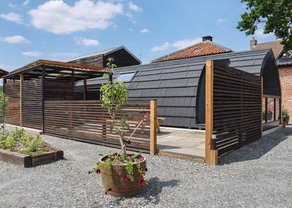 ein schwarzes Gebäude mit einem Holzzaun im Hof in der Unterkunft Hill Farm Retreat in Wangford