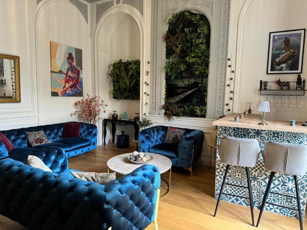 ein Wohnzimmer mit blauen Sofas und einem Tisch in der Unterkunft Prestigieuse Suite Princeteau in Libourne