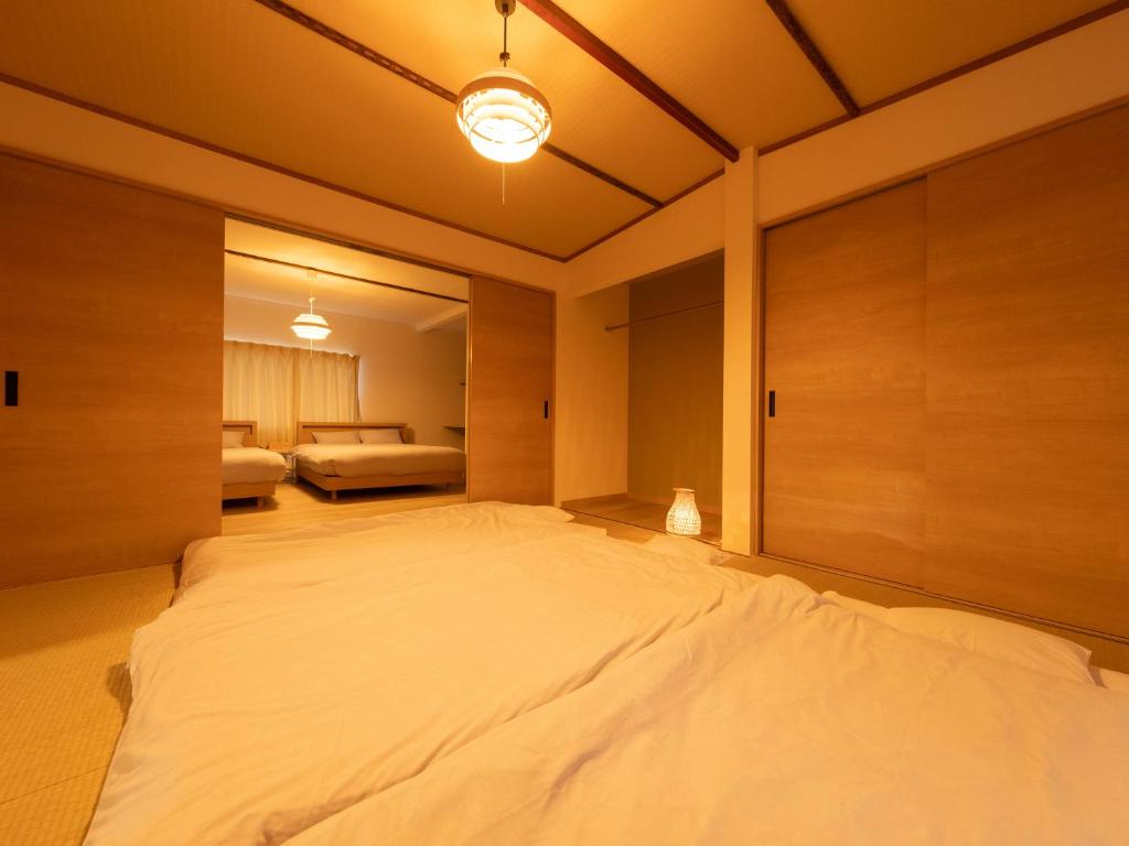een groot wit bed in een kamer met een slaapkamer bij かんたろうもねたろうの母家 in Furano