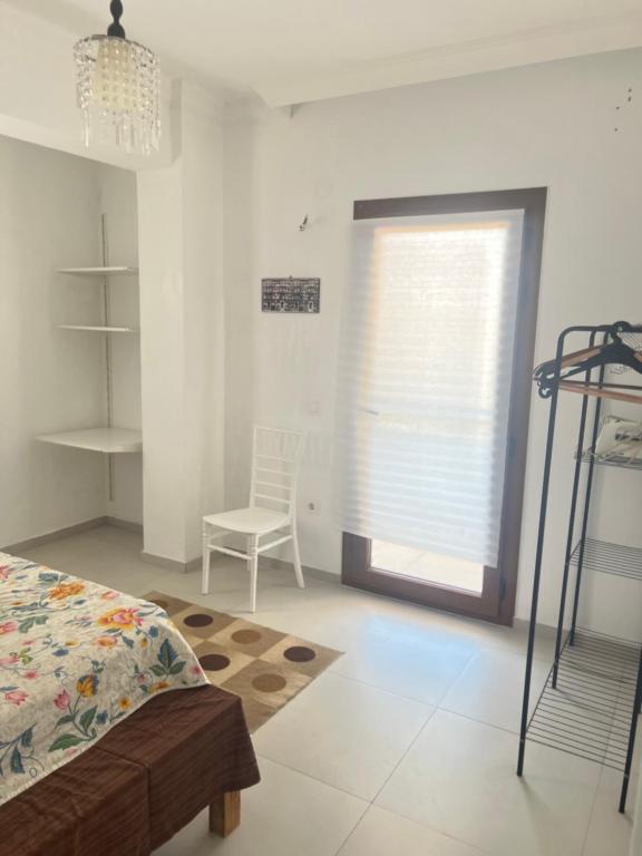 a bedroom with a bed and a window with a chair at Azra evleri in Datca