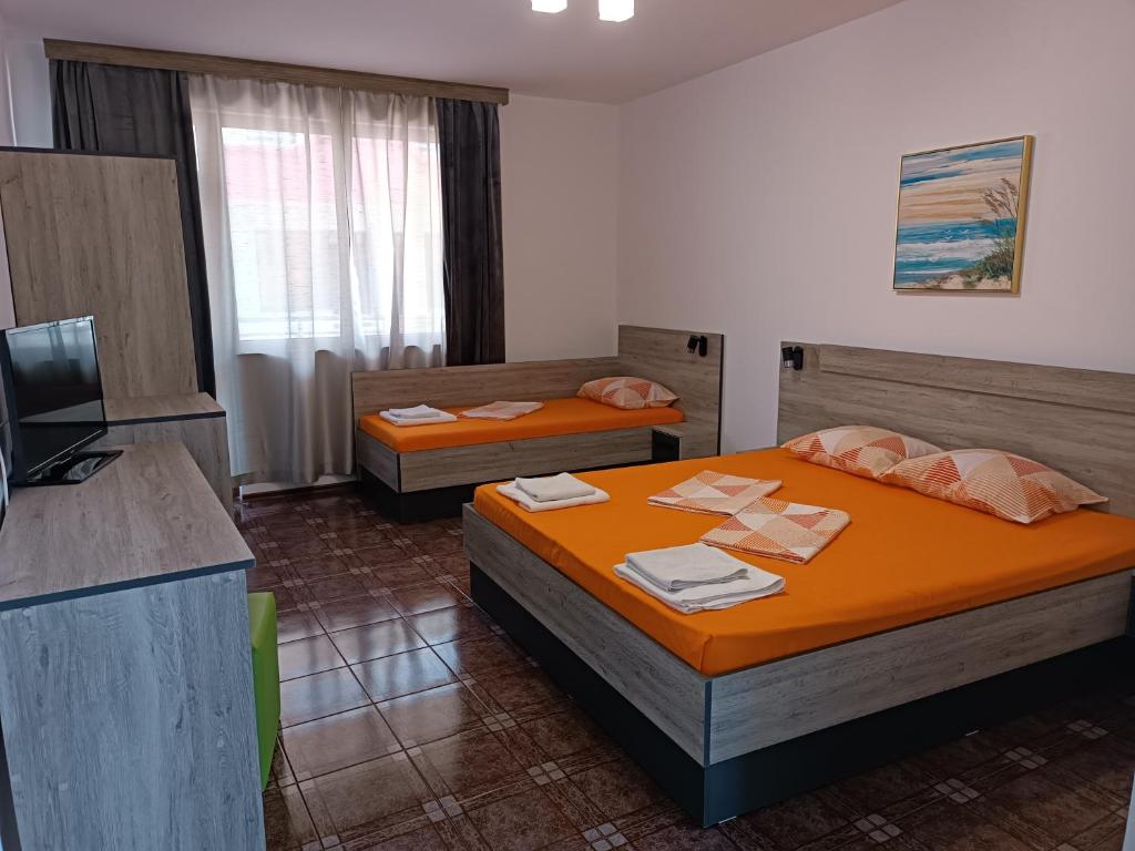 a hotel room with two beds and a television at Coral Family Hotel in Chernomorets