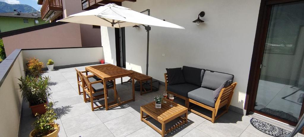 um pátio com uma mesa, cadeiras e um guarda-sol em Le quattro stagioni em Levico Terme