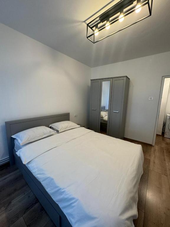 a bedroom with a large white bed and a light at Peony Apartament in Craiova