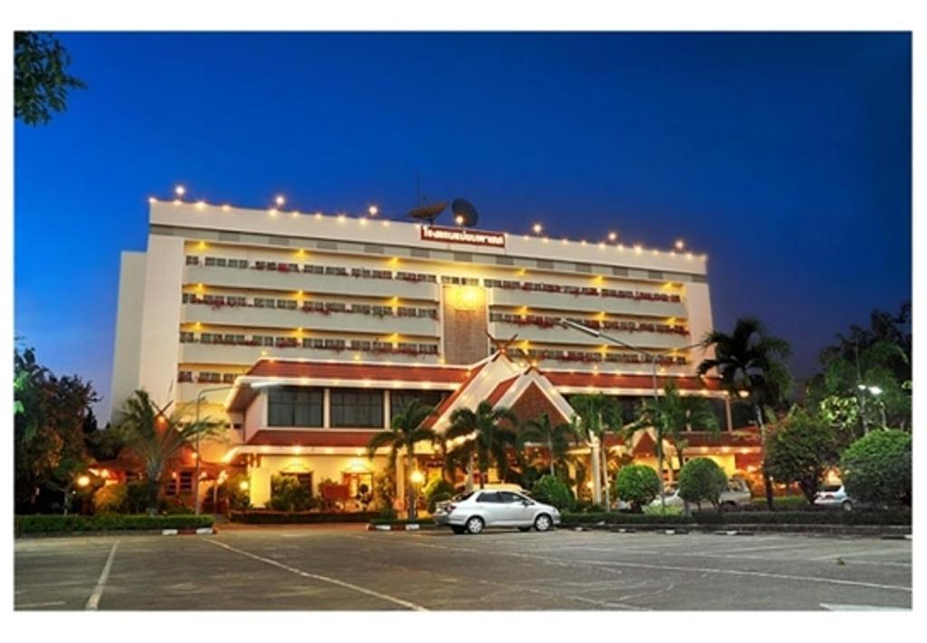 un hotel con un coche aparcado en un aparcamiento en Maeyom Palace Hotel, en Phrae