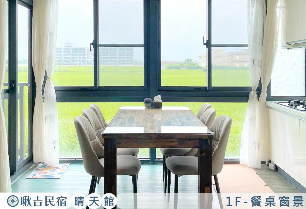 uma sala de jantar com mesa, cadeiras e janelas em 啾吉民宿晴天館 em Wujie