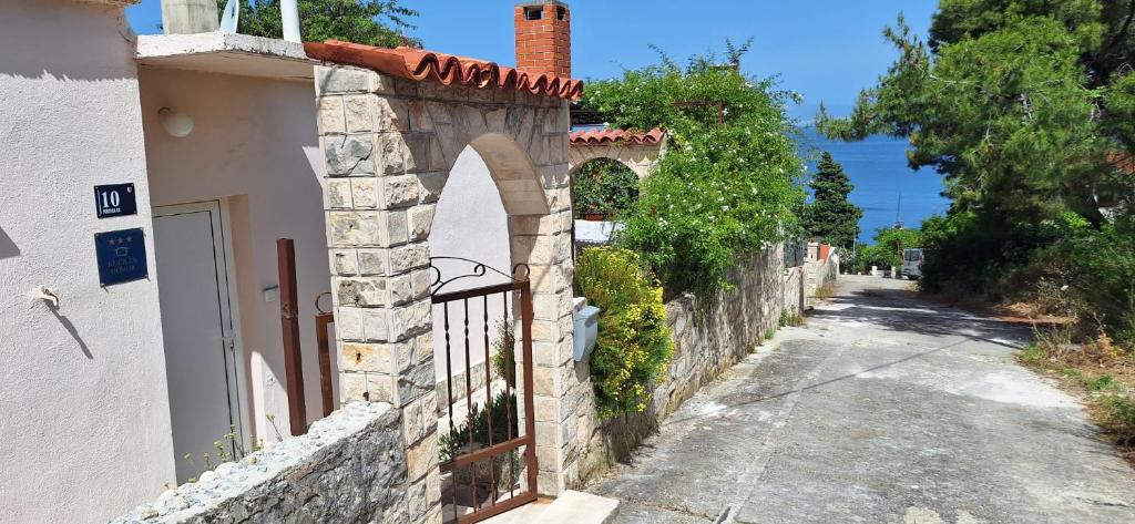 einen Steinzaun neben einem Gebäude mit einem Tor in der Unterkunft Kuća za odmor Skalina in Splitska