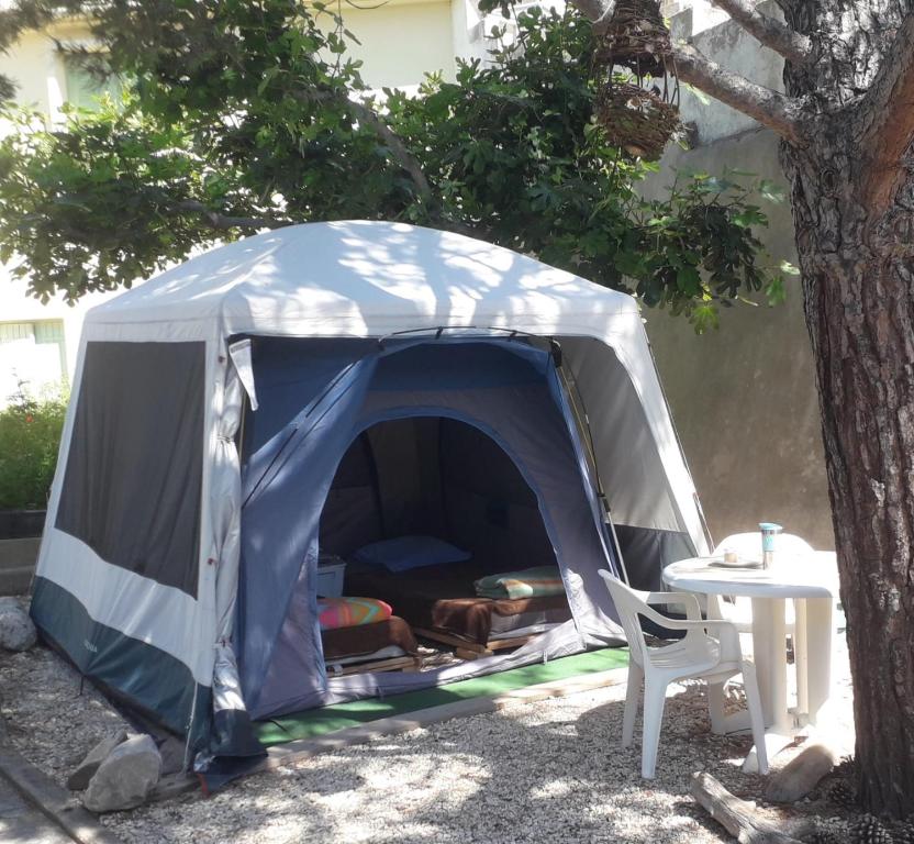 een blauwe en witte tent naast een tafel bij Deux tentes confortables dans un joli jardin idéalement situé in Sète