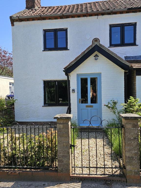 a white house with a blue door at Rosemary Cottage in Mattishall