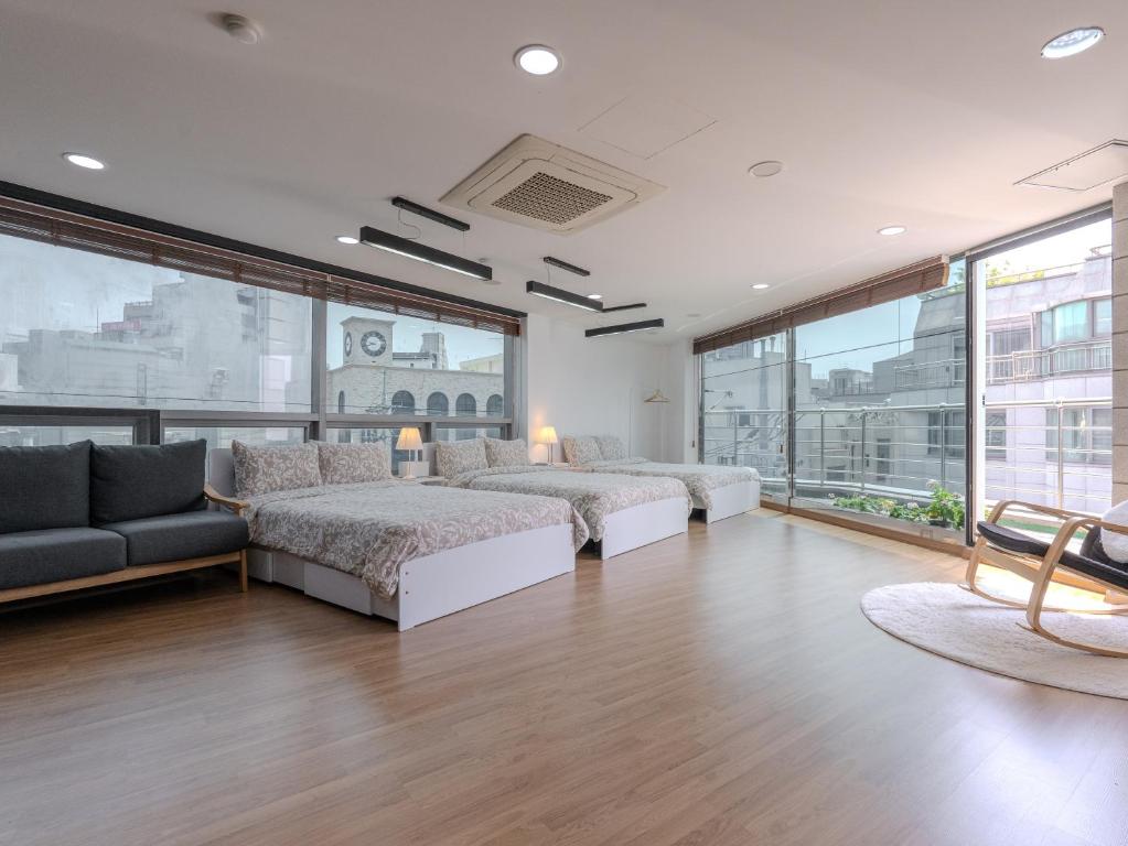 a bedroom with two beds and a couch and windows at Harmony Stay in Seoul