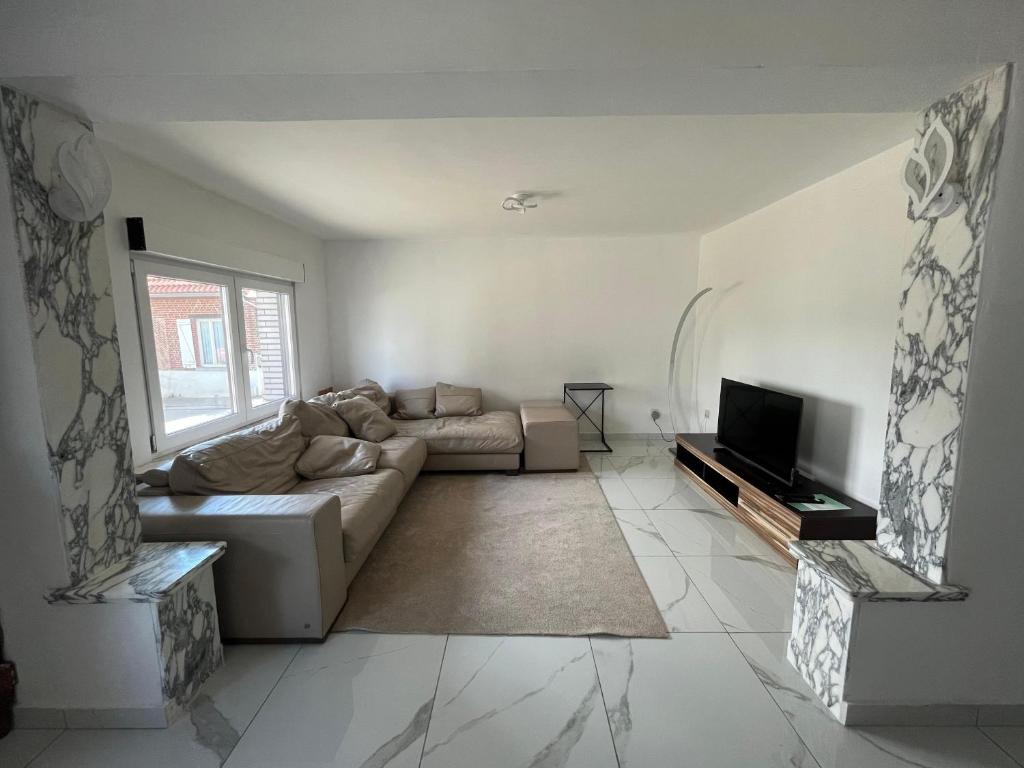 ein Wohnzimmer mit einem Sofa und einem TV in der Unterkunft Chez Nadège in Affligem