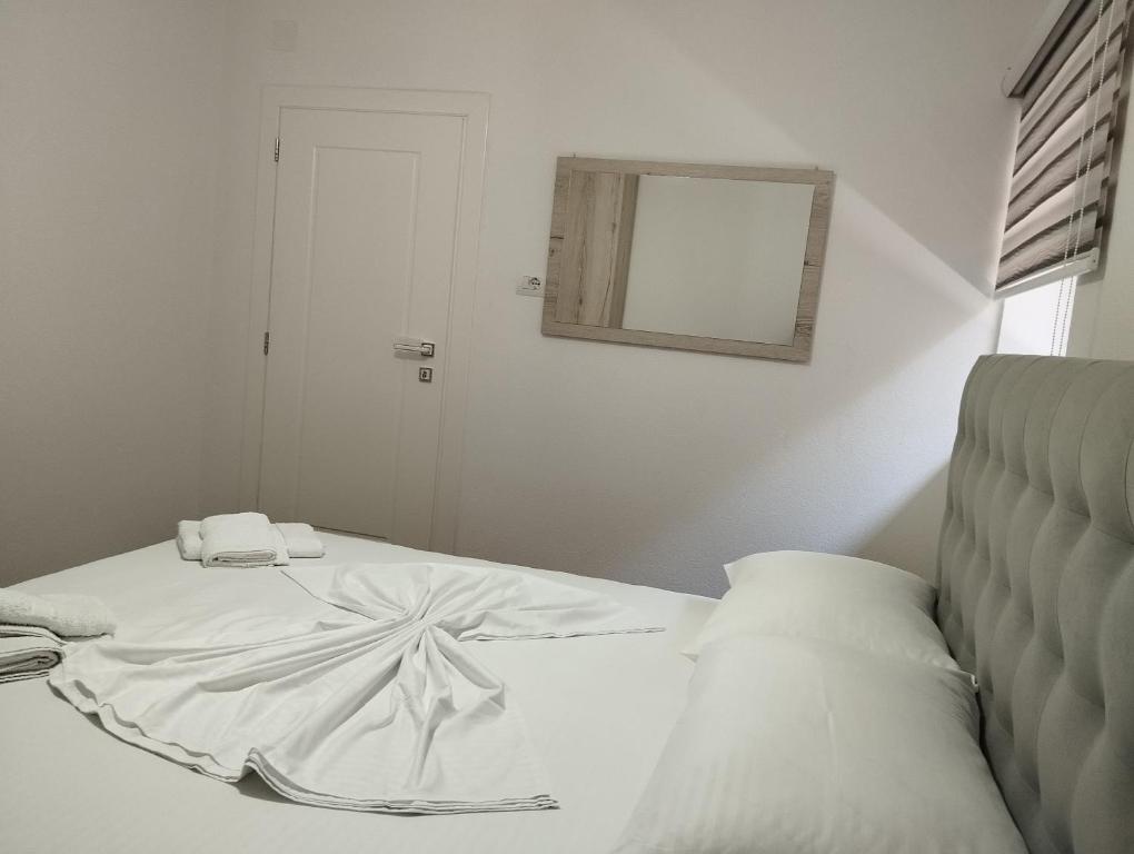 a bedroom with a white bed with a mirror at ERTEO Guest House in Pogradec