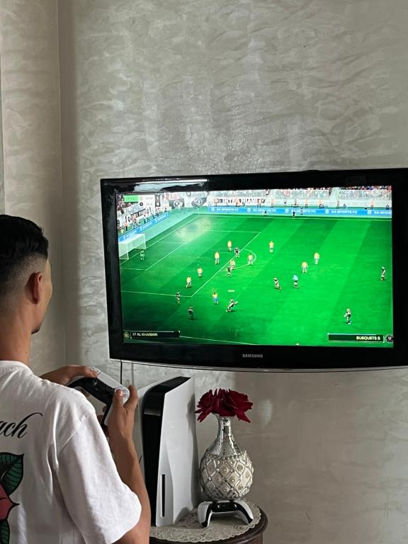 a man playing a video game on a television at M'a Raffiné appartement 2 in Casablanca