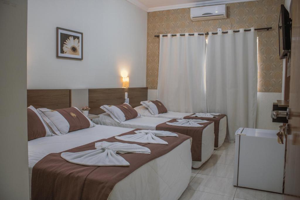 Tres camas en una habitación de hotel con toallas. en Hotel do Reinildo I, en Cachoeira Paulista