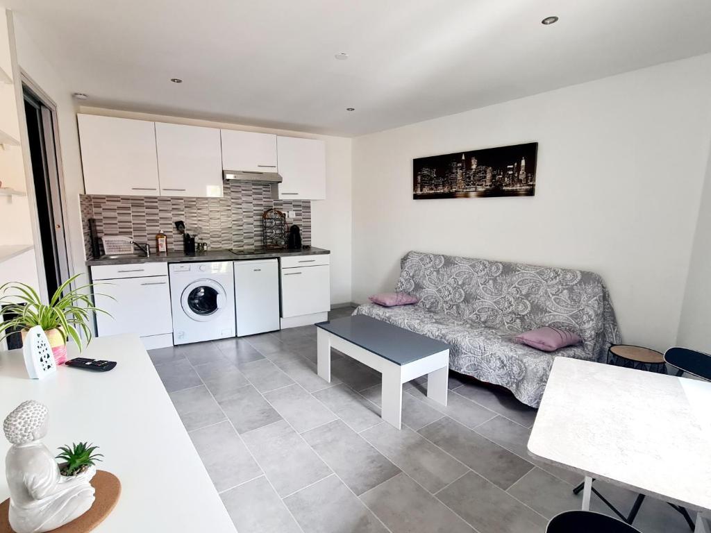 ein Wohnzimmer mit einem Sofa und einer Küche in der Unterkunft Studio HELTYMIE 4-Vélos bienvenus-parking gratuit in Portiragnes