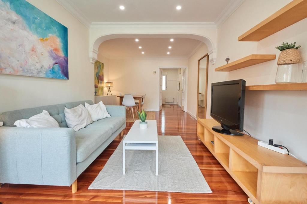 a living room with a blue couch and a tv at Apartamento Primera Linea SARDINERO - RH Santander in Santander