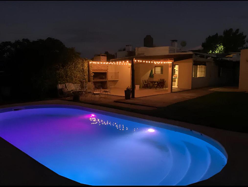 a blue swimming pool at night with a house at CCasa con piscina para 8 personas in Mercedes