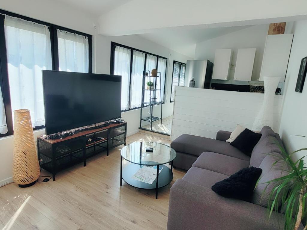 un salon avec un canapé et une télévision à écran plat dans l'établissement Maison de ville au calme avec jardin et parking, à La Rochelle