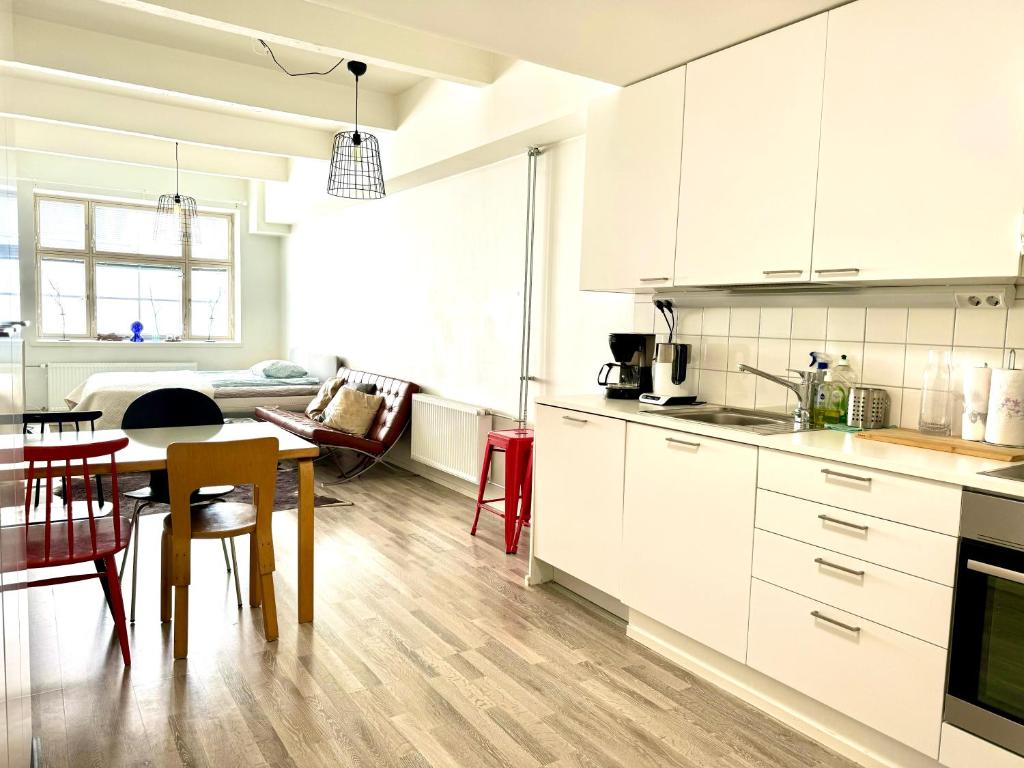 a kitchen with white cabinets and a table and chairs at Factory Studio in Helsinki