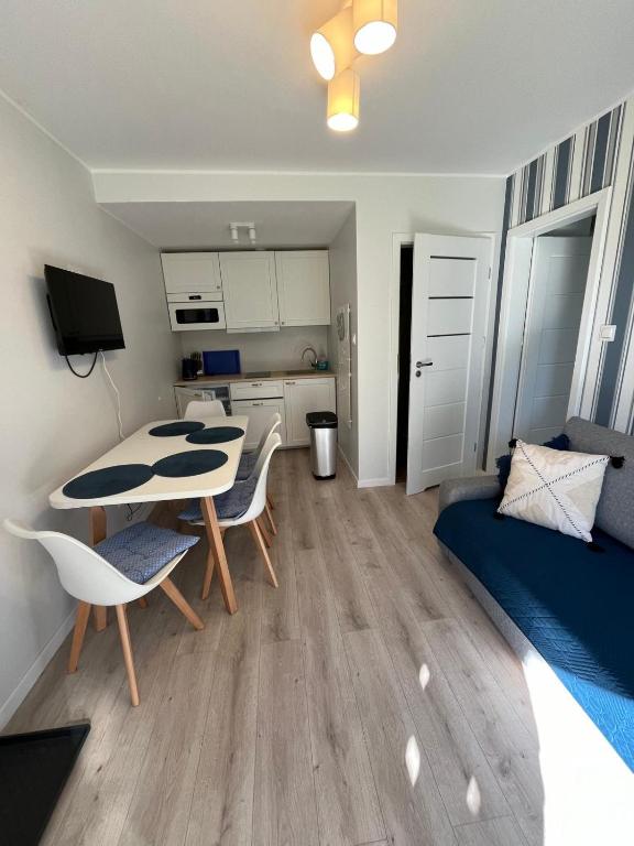 a living room with a table and chairs and a bedroom at Apartament Szept Morza in Debina