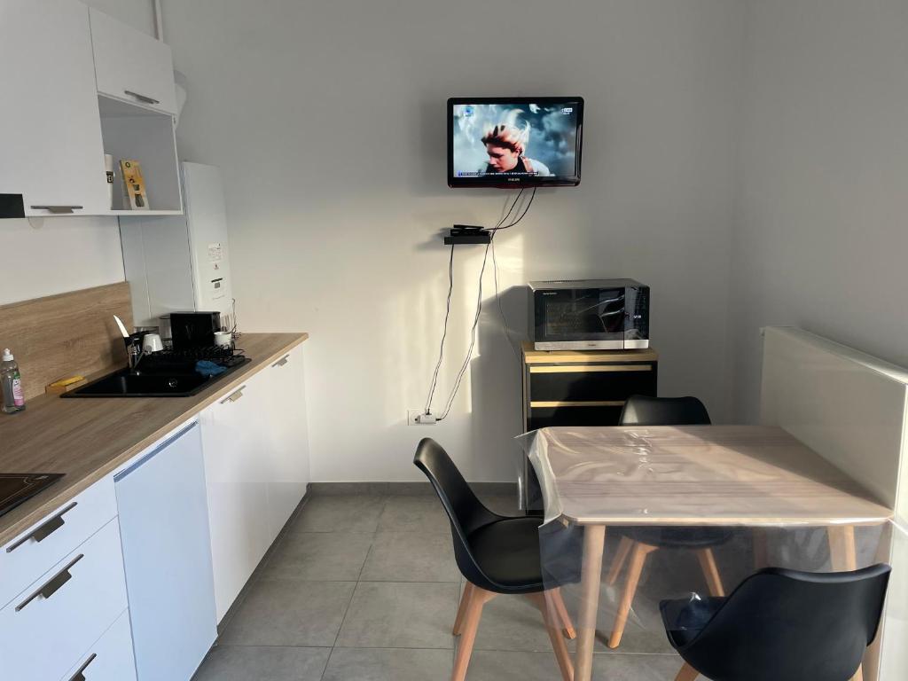 kuchnia ze stołem i krzesłami oraz telewizor na ścianie w obiekcie Les chti picards w mieście Berck-sur-Mer