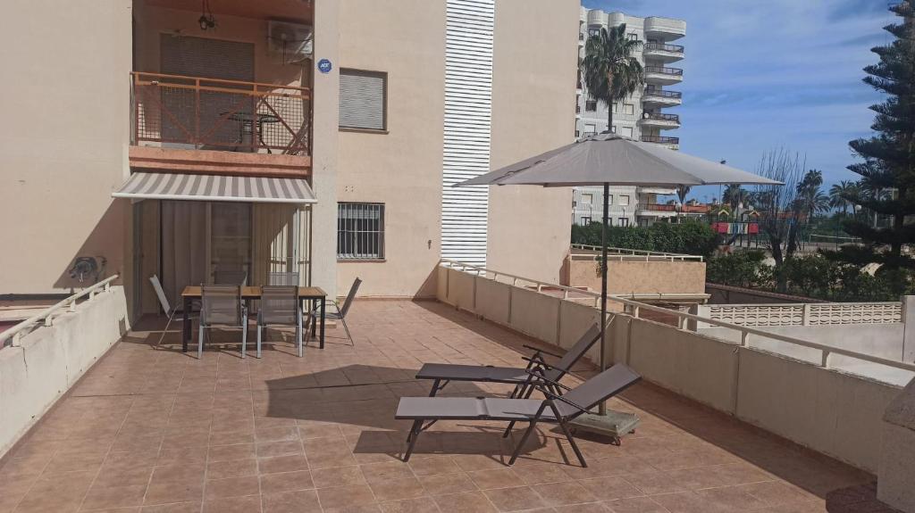 - une terrasse avec des chaises et un parasol dans un bâtiment dans l'établissement Mikonos, à Gandía