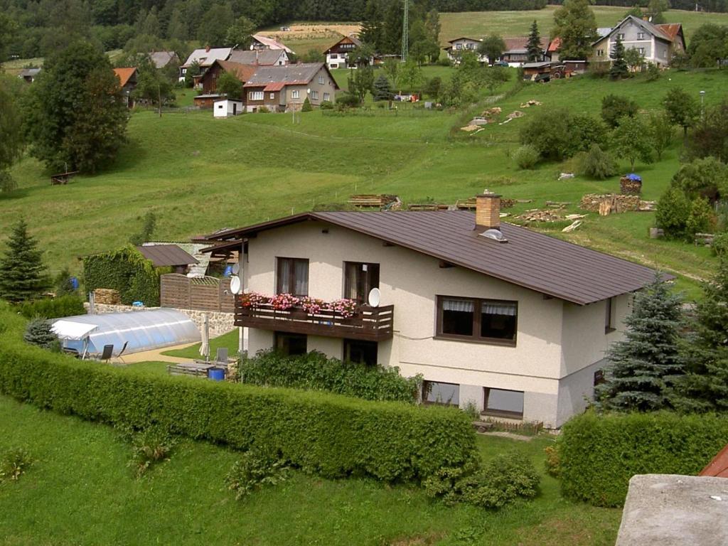 een wit huis in een groen veld met een huis bij Guest House Bulušek in Rokytnice nad Jizerou