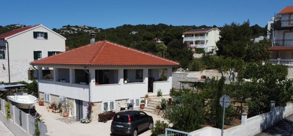 a car parked in front of a house with a red roof at Green Garden , HOMEANDSAIL in Jezera