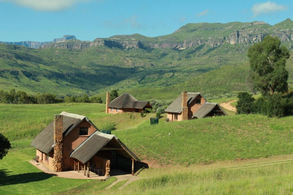 eine Gruppe von Häusern auf einem Feld mit Bergen im Hintergrund in der Unterkunft Top Lodge in Bonjaneni