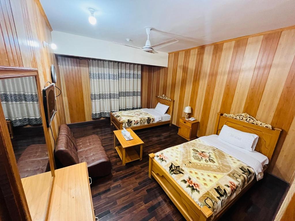 a hotel room with two beds and a couch at Blue Sky Hotel & Restaurant in Skardu