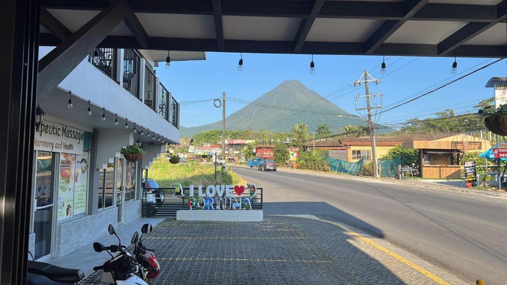 a motorcycle parked on a street with a mountain in the background at Hotel Arenal by Regina in Fortuna