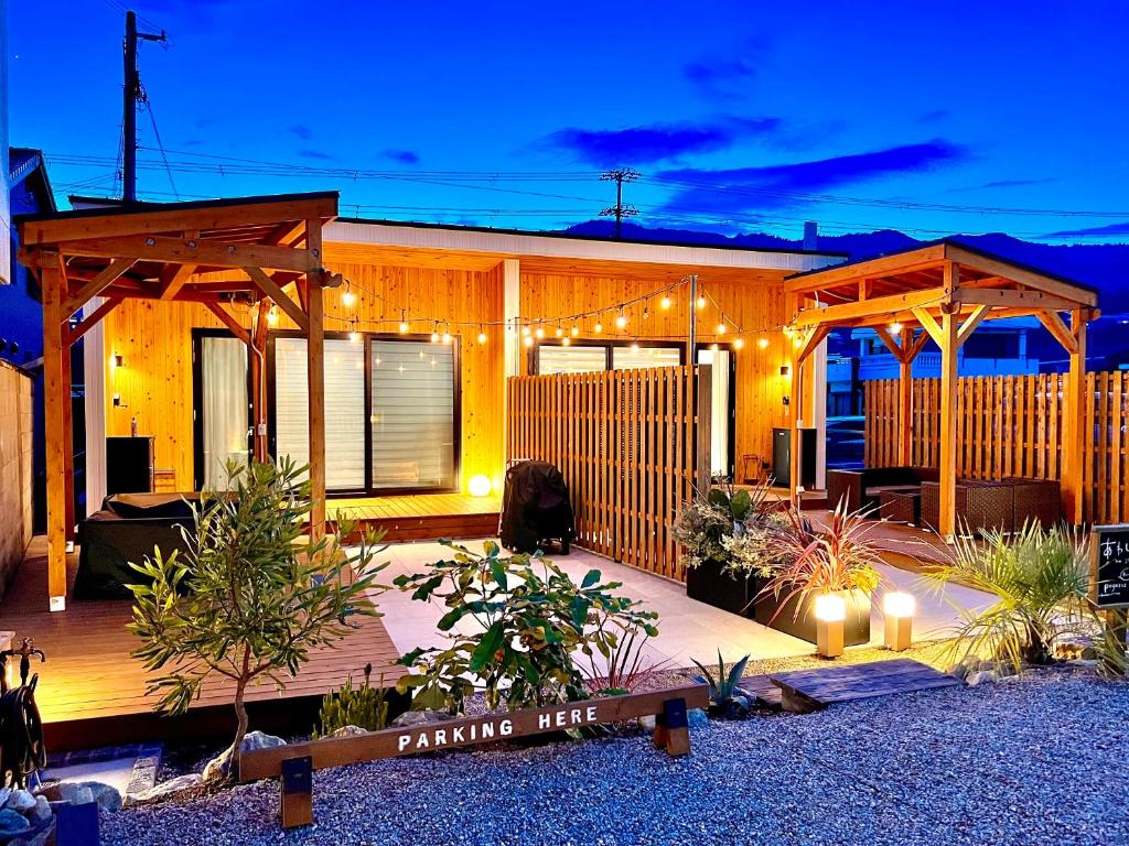 ein Haus mit einer Holzterrasse mit Beleuchtung in der Unterkunft Rush Awaji - Seaside Holiday Home - Self Check-In Only in Awaji