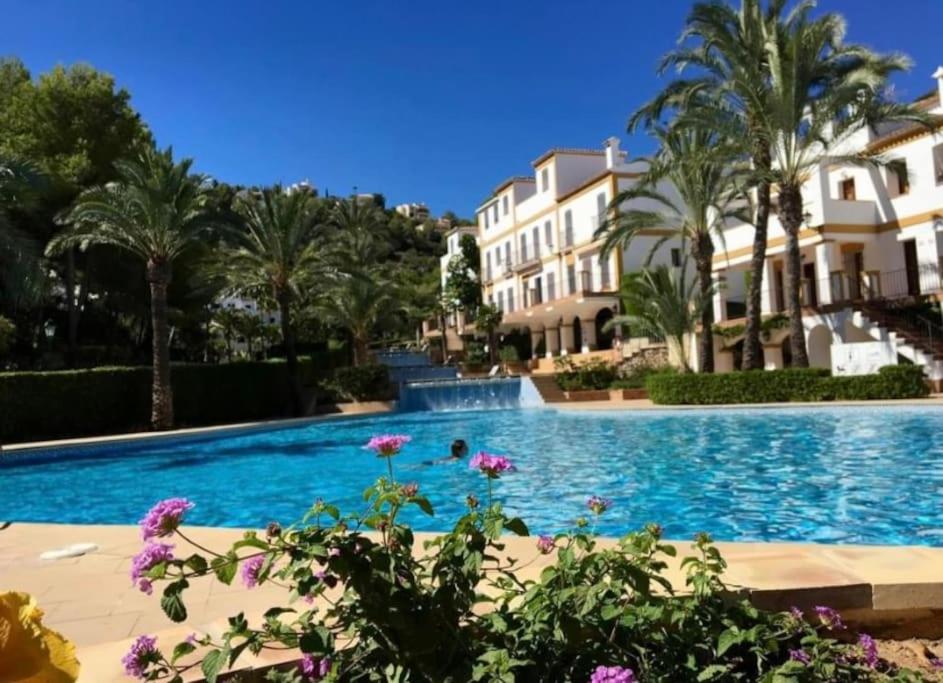 a swimming pool with palm trees and houses at Charming 3-storey house at residential golf resort in Muntanya la Sella