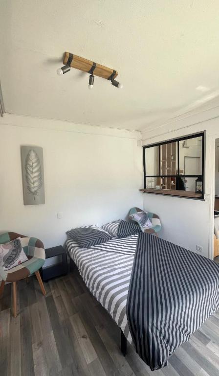 - une chambre avec un lit rayé et une fenêtre dans l'établissement Résidence Beau Séjour, à Amélie-les-Bains-Palalda