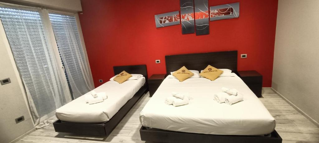 2 Betten in einem Zimmer mit roten Wänden in der Unterkunft Millaenya Inn in Entratico