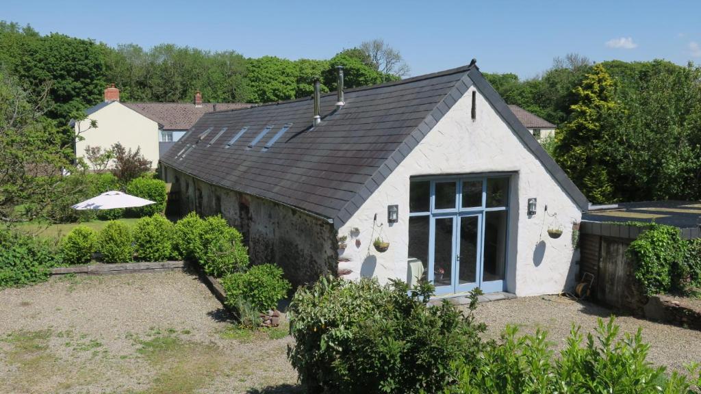 un petit bâtiment blanc avec un toit noir dans l'établissement The Old Cowshed, à Pembroke