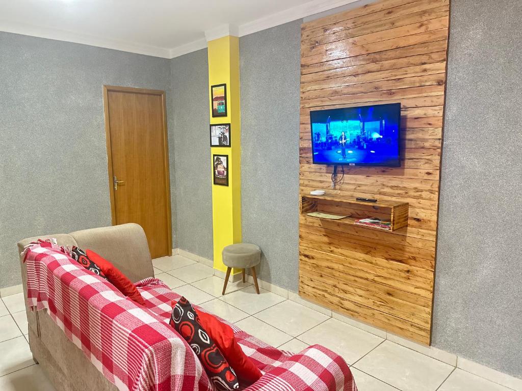salon z kanapą i telewizorem na ścianie w obiekcie AP+preço popular+ar condicionado+internet 300mb w mieście Goiânia