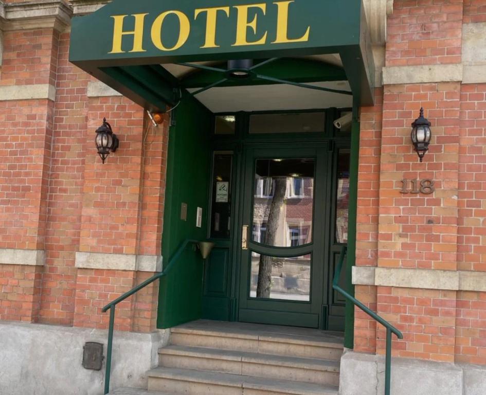 Hotel Amadeus Dresden Neustadt في درسدن: مدخل الفندق مع وجود باب أخضر على مبنى من الطوب