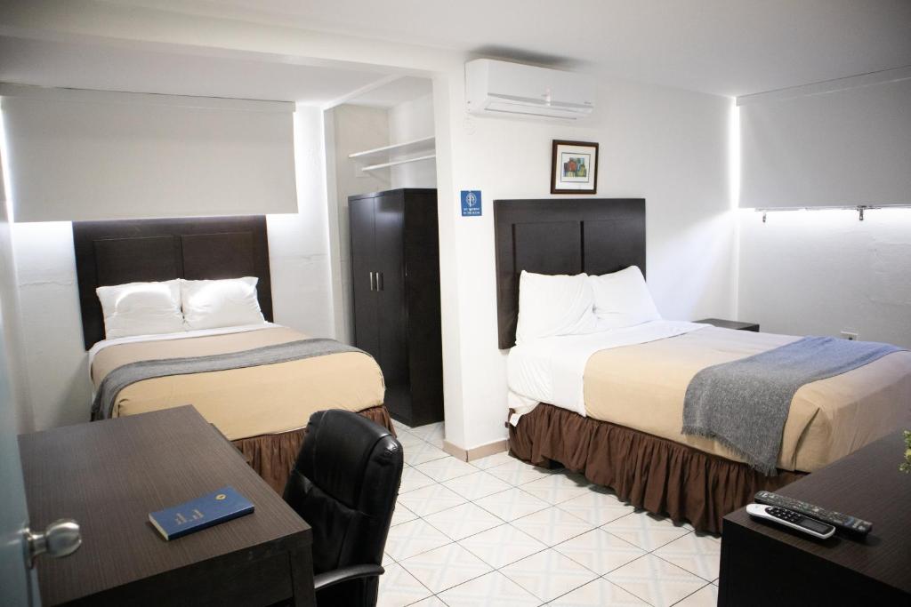 Borinquen Beach Inn في سان خوان: غرفة فندقية بسريرين وطاولة