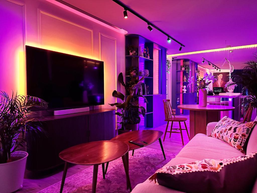 ein Wohnzimmer mit einem Sofa und einem TV sowie lila Beleuchtung in der Unterkunft Ambient lounge with sundeck and free parking in Bratislava