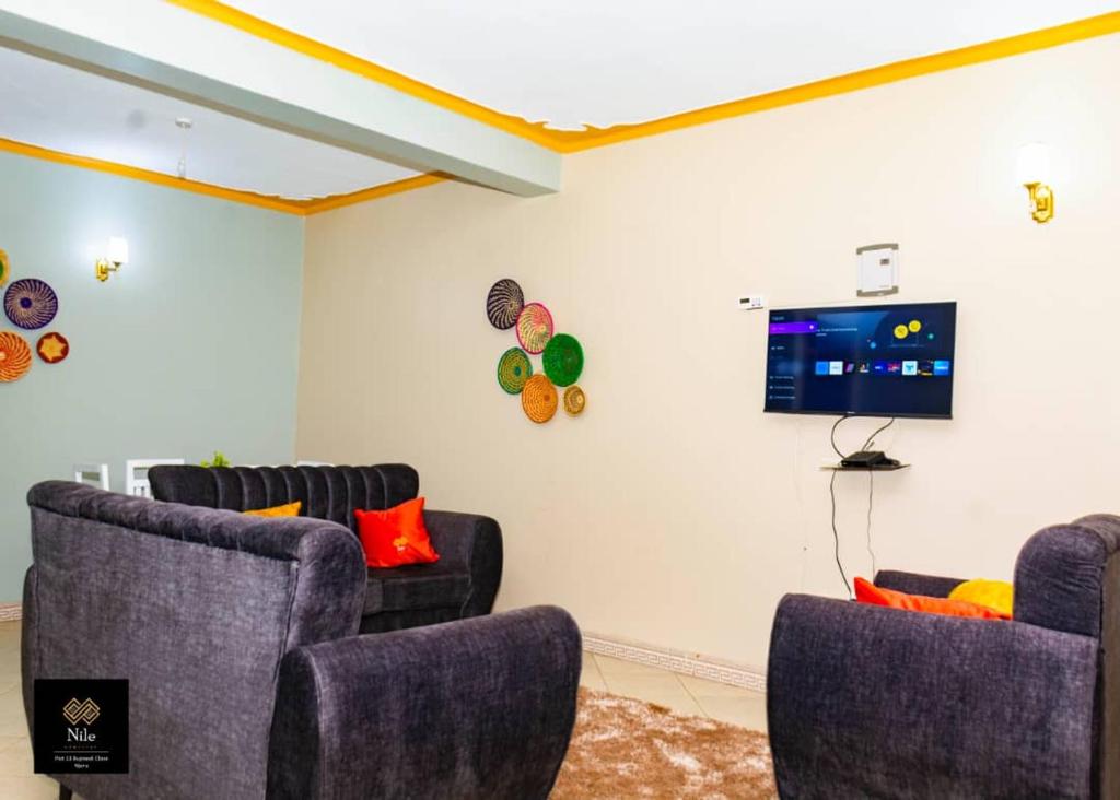 a living room with three chairs and a flat screen tv at Nile Homestay in Jinja