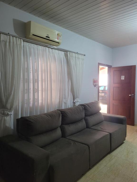sala de estar con sofá marrón frente a una ventana en Casa centro jipa en Ji-Paraná