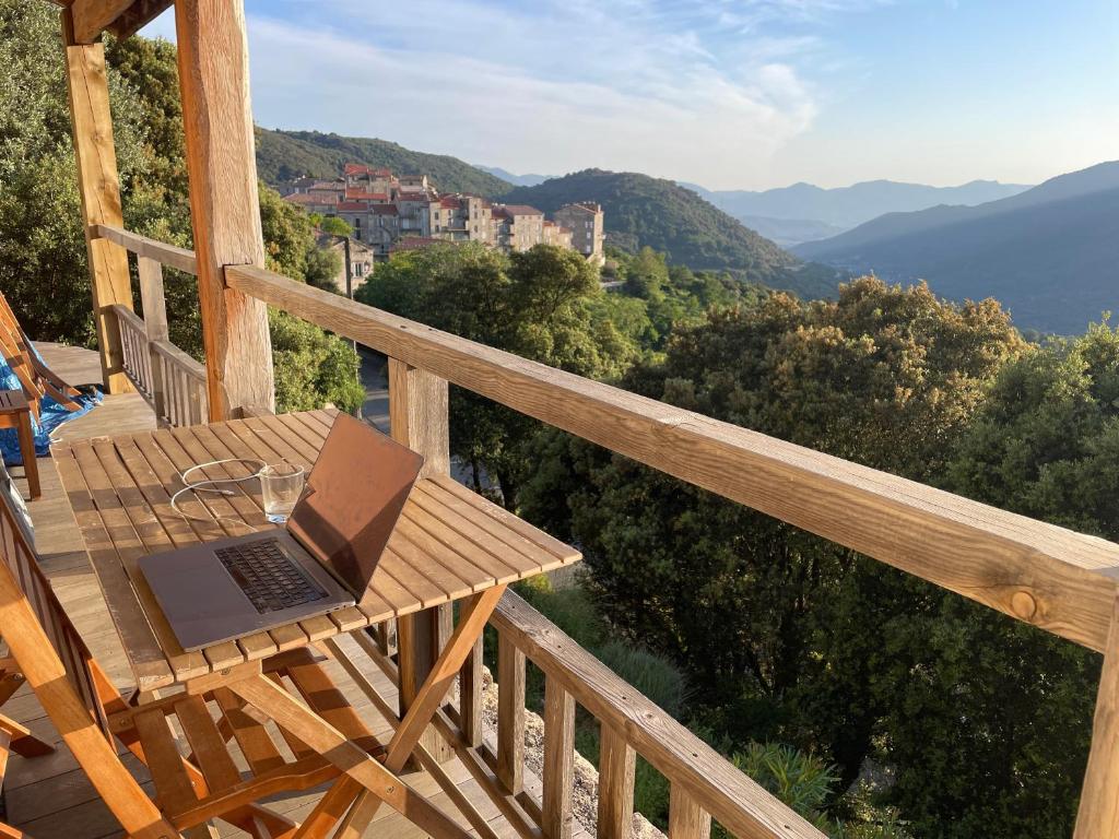un ordinateur portable assis sur une table en bois sur un balcon dans l'établissement Maison indépendante à Sainte-Lucie de Tallano, à Santa-Lucia-di-Tallano