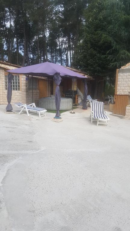 un groupe de chaises et un parapluie violet dans l'établissement Paisible Chalet, à Largentière
