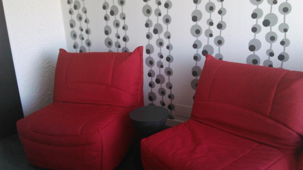 two red chairs sitting next to each other in a room at Hôtel Le Nautic in Arcachon
