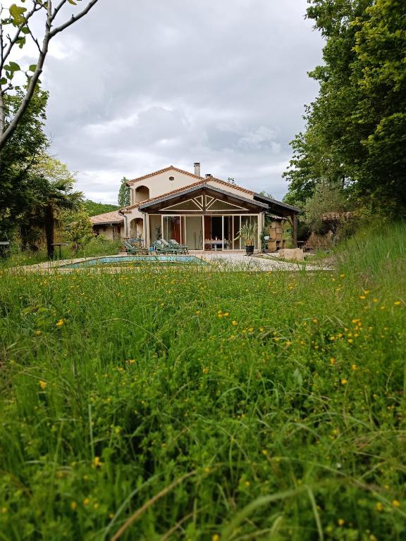 une maison avec un champ d'herbe devant elle dans l'établissement Maison de vacances authentique, à Castelnau-de-Montratier