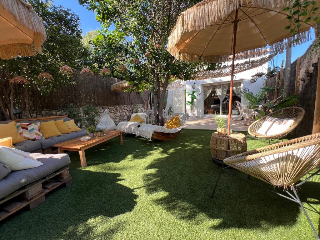 een tuin met een bank, stoelen en een parasol bij Maisonnette avec terrasse et jardin-Parking privé-9mn des plages à pied in La Ciotat