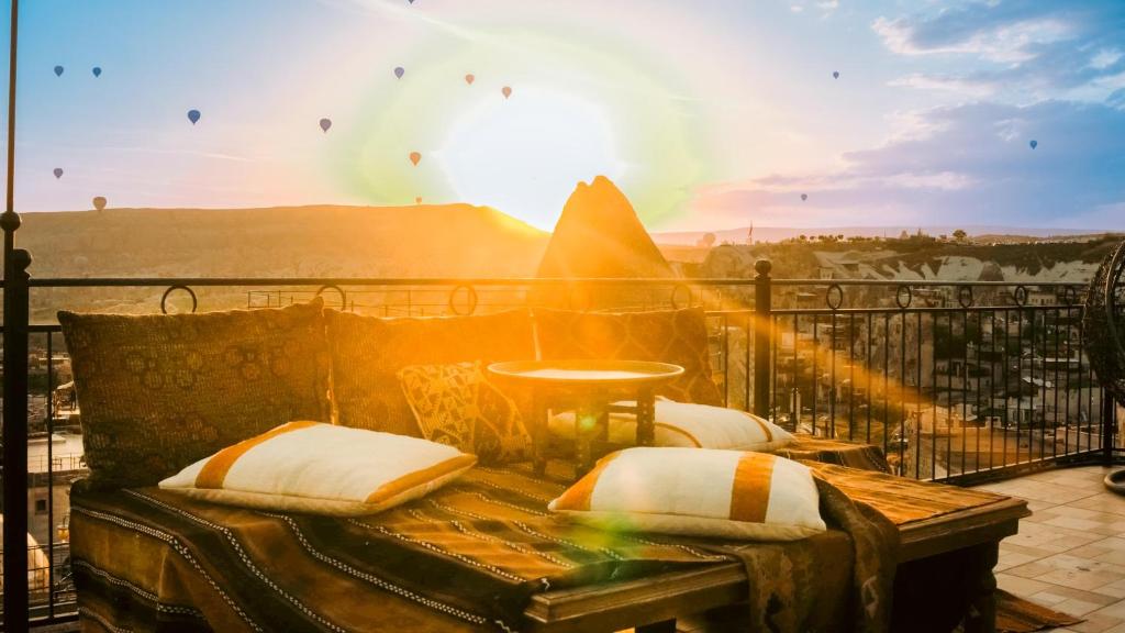 een balkon met een bank met de zon op de achtergrond bij Salkım Cave House in Goreme